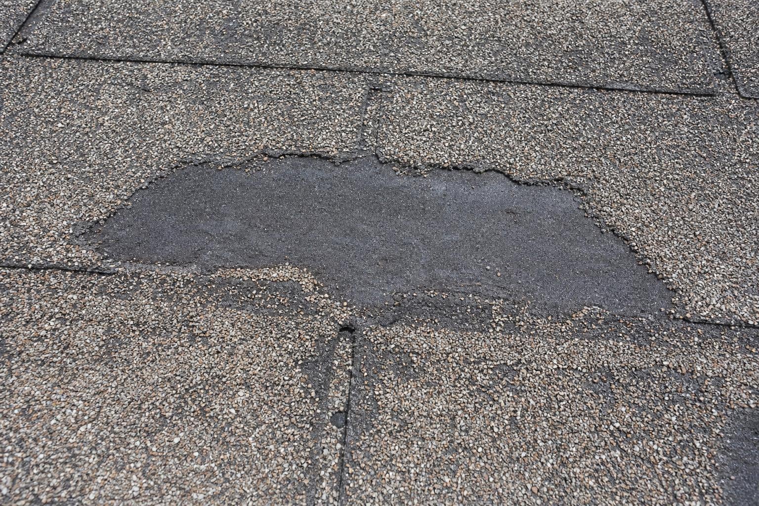 Asphalt shingle roof in Rapid City SD with severe granule loss exposing the dark asphalt mat
